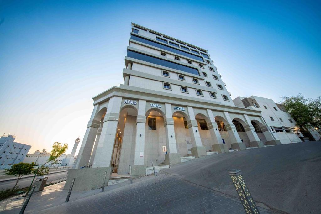 a large white building with a tower on a street at Afaq Taiba Hotel in Medina
