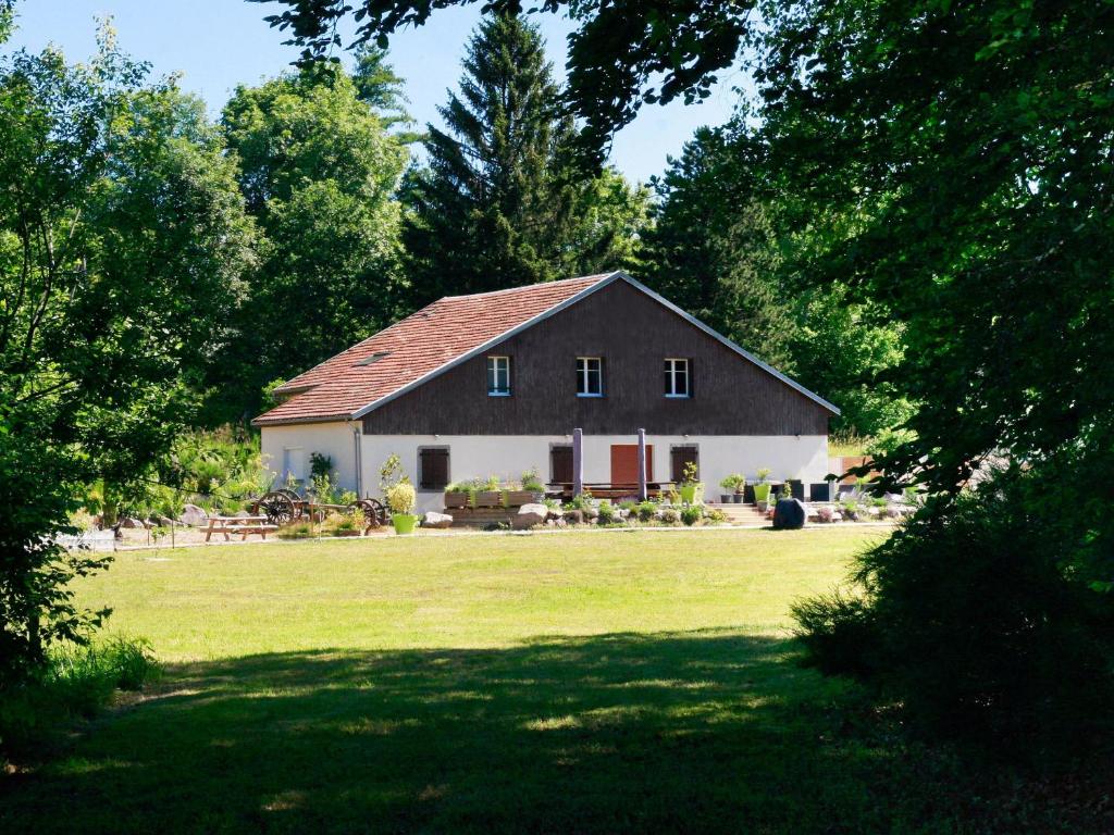 a house in a field of grass with trees at Ferme Vosgienne rénovée avec spa, sauna, jacuzzi, billard et étang privé en pleine nature - FR-1-589-327 in Saulxures-sur-Moselotte