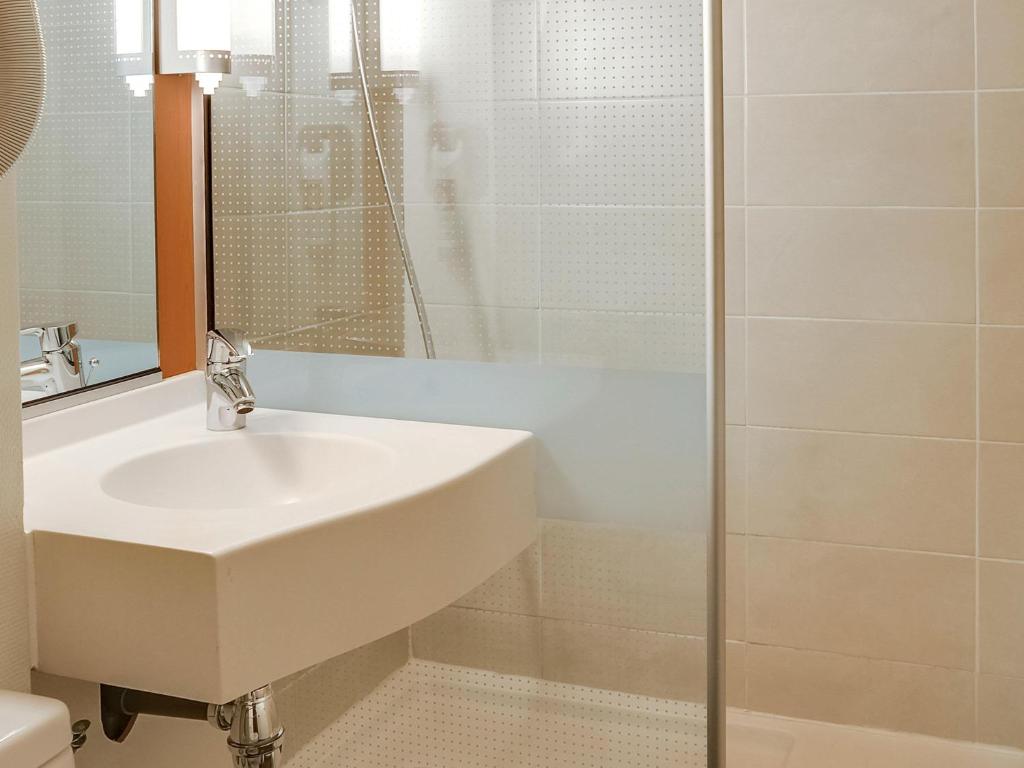 ein weißes Badezimmer mit Waschbecken und Dusche in der Unterkunft ibis Salon de Provence in Salon-de-Provence