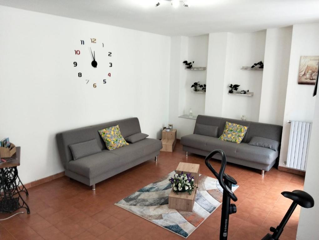 ein Wohnzimmer mit zwei Sofas und einer Uhr an der Wand in der Unterkunft Appartamento di Marilù in Verbania