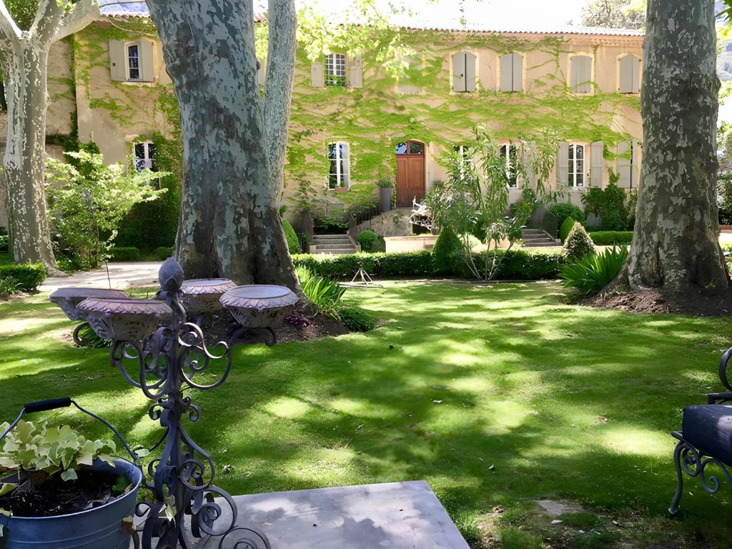 a garden with two trees and a bench and a building at Château De Jouques in Gémenos