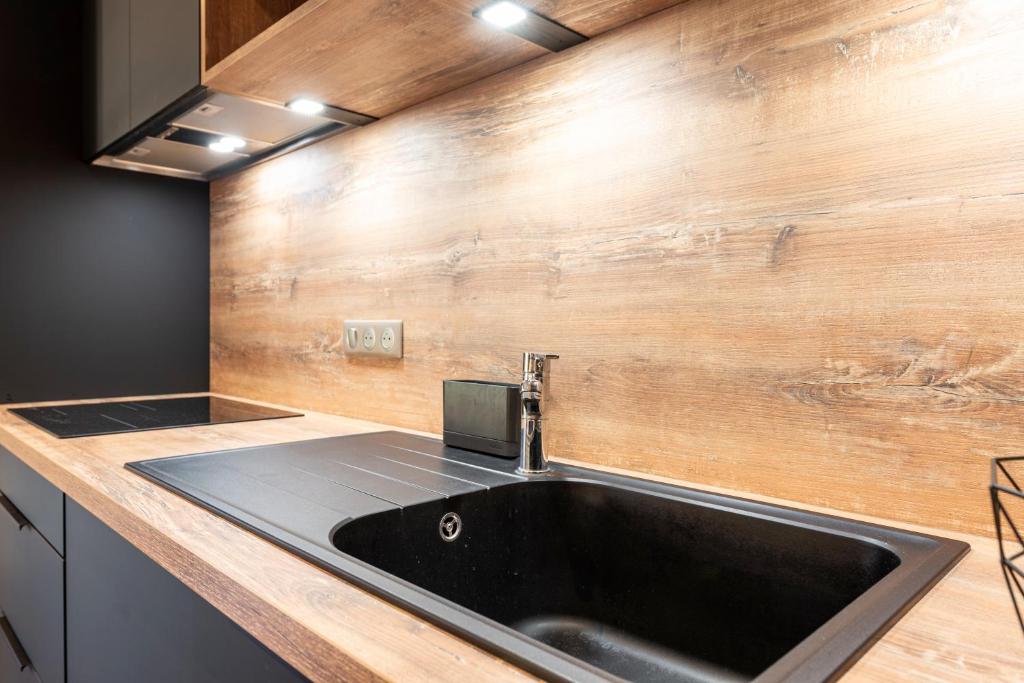 Le Zelfée appartement de 4 personnes à Albiez-Montrond في ألبيز-مونتروند: مطبخ مع حوض وجدار خشبي