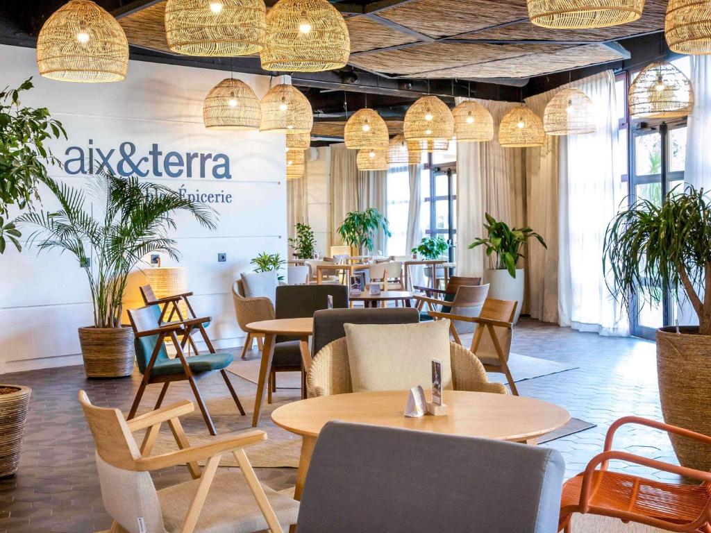 a restaurant with tables and chairs and potted plants at Mercure Cannes Mandelieu in Cannes