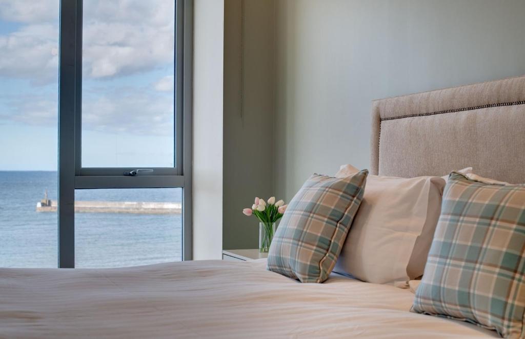 een slaapkamer met een bed met uitzicht op de oceaan bij Harbour Heights Seahouses in Seahouses