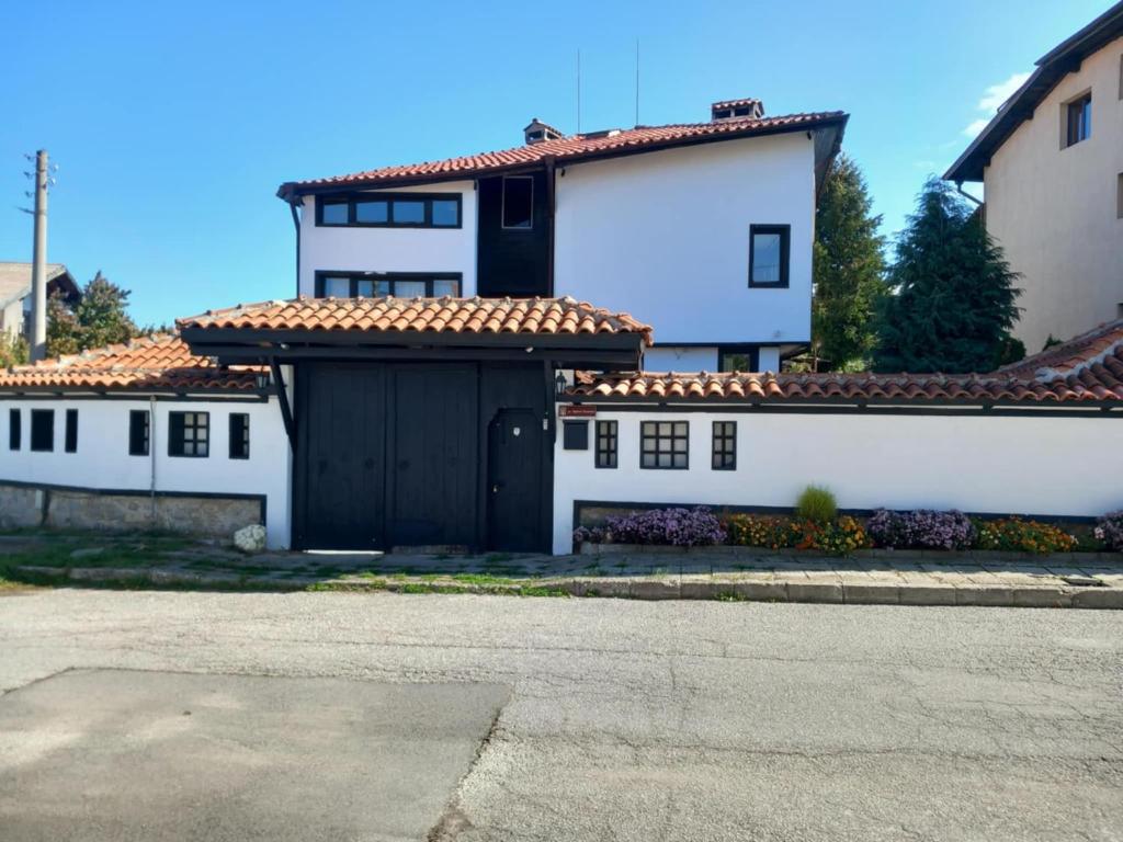 a large white house with a black garage at Villa TIANA Bansko 7-Bedroom Luxury Chalet in Bansko