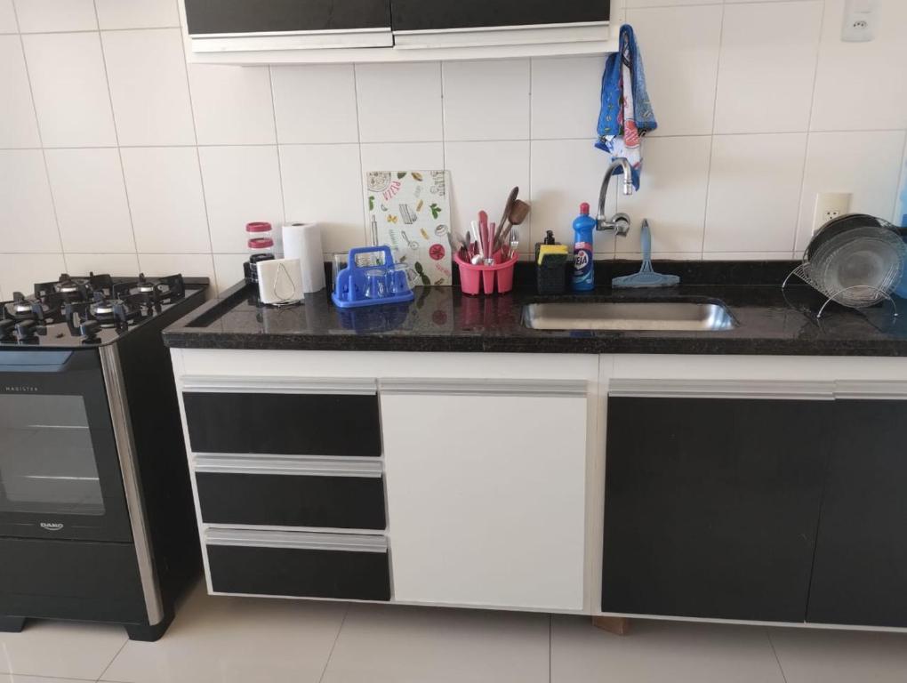 a kitchen counter with a sink and a stove at Apartamento 200 metros da praia e próximo a comércios in Rio das Ostras