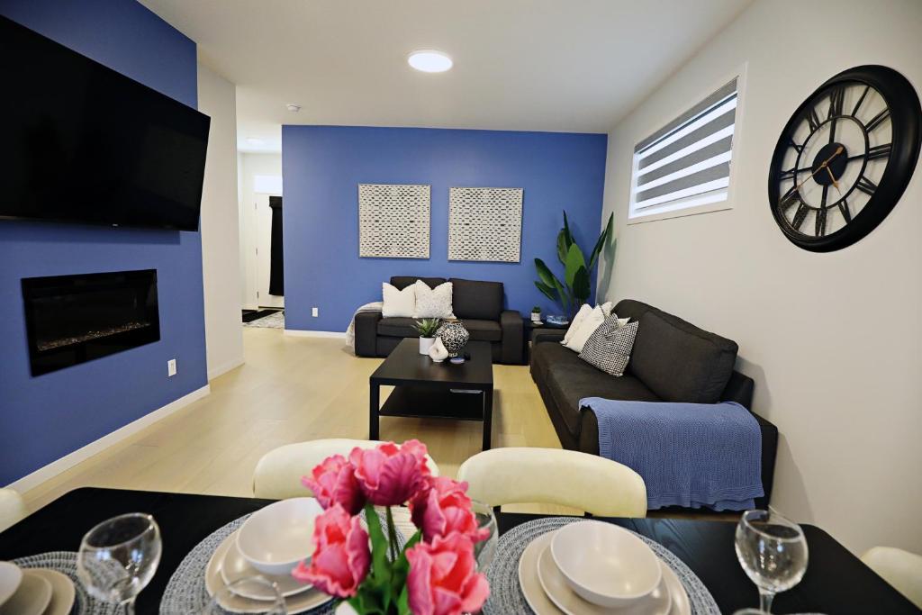 a living room with a couch and a clock on the wall at Seton 4BR Family Home King Bed Near Hospital in Calgary