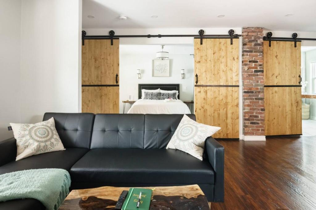 ein Wohnzimmer mit einer schwarzen Couch vor einem Bett in der Unterkunft Wood-Rich Niagara Loft close to Queen Street in Niagara Falls