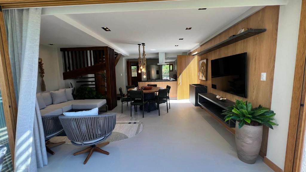 a living room with a couch and a dining room at Reserva dos jacarandás praia do forte in Praia do Forte