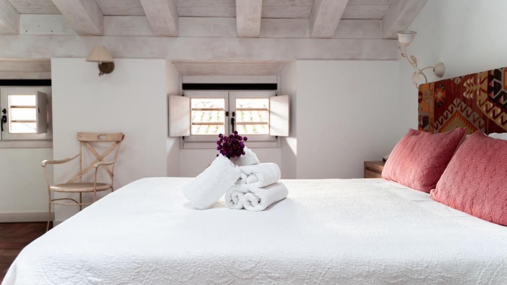a bedroom with a white bed with two stuffed animals on it at Hotel El Cerco in Puente la Reina