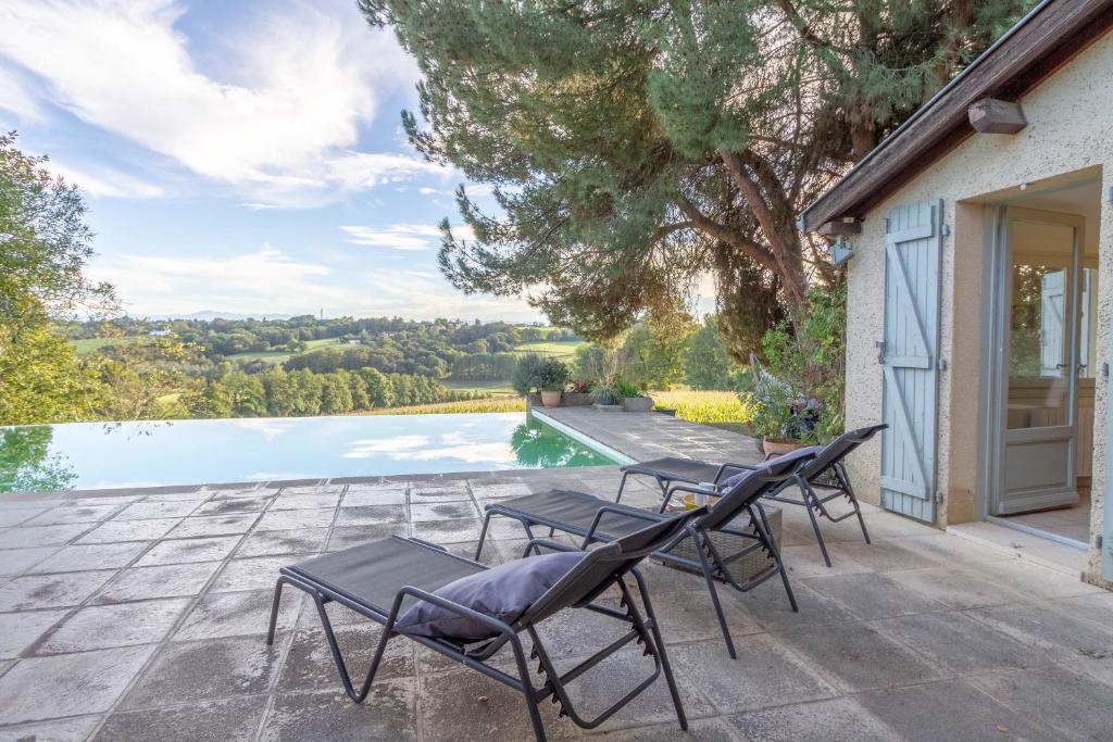 a patio with chairs and a swimming pool at Villa Roumentas - 8 pers - Vue vallée & Piscine in Navailles-Angos