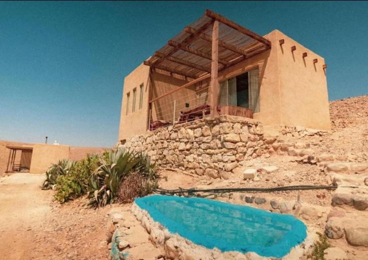 a house in the desert with a blue pool in front at Amara Escape in Zuqim