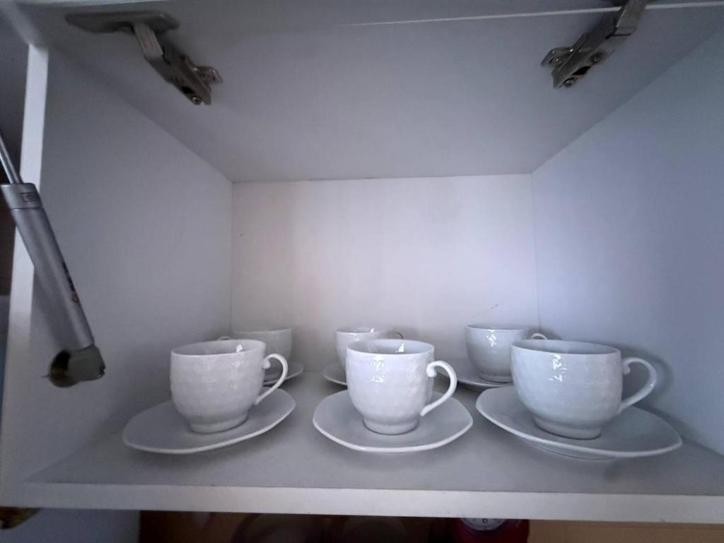 a shelf with four cups and saucers on it at Апартаменты на СОВЕТСКОЙ 39 in Petropavlovsk