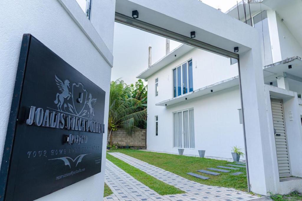 een wit gebouw met een bord ervoor bij Joalis Villa Polhena Ltd in Matara
