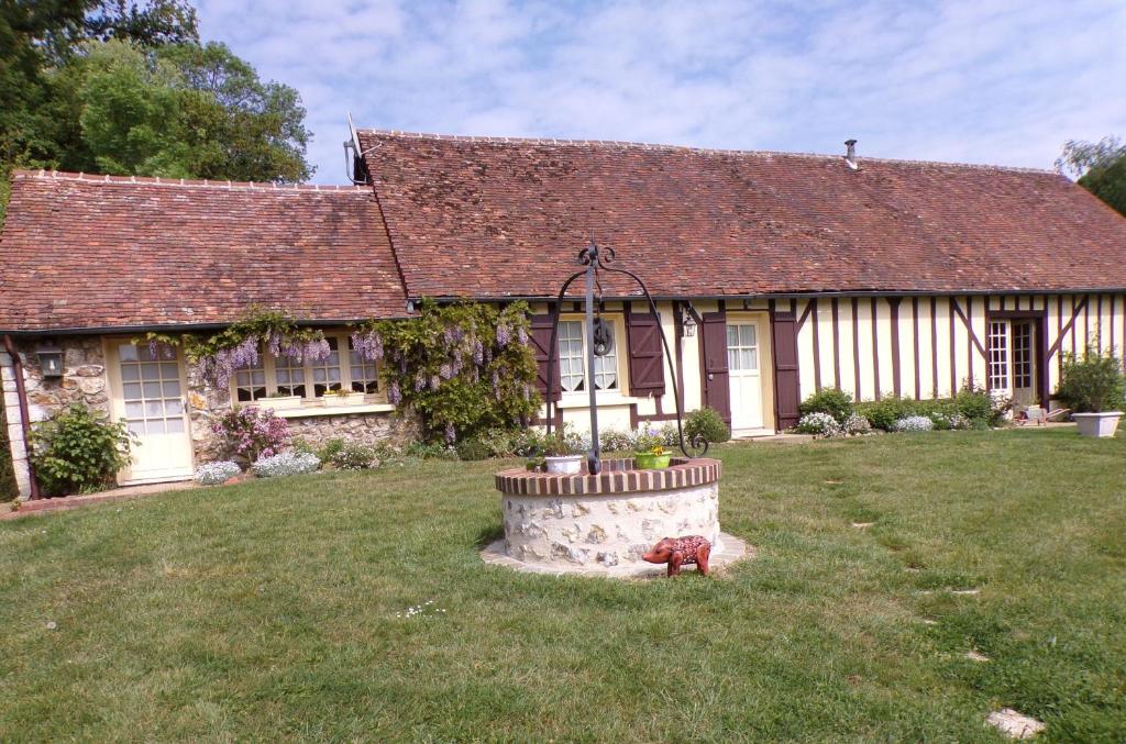an old fashioned house with a flower pot in the yard at Gîte aux Portes du Perche in Unverre