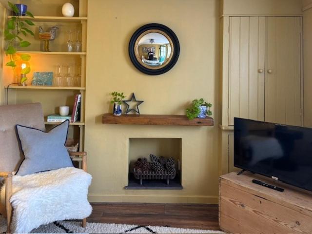ein Wohnzimmer mit einem TV und einem Kamin in der Unterkunft Havelock Cottages in Oundle