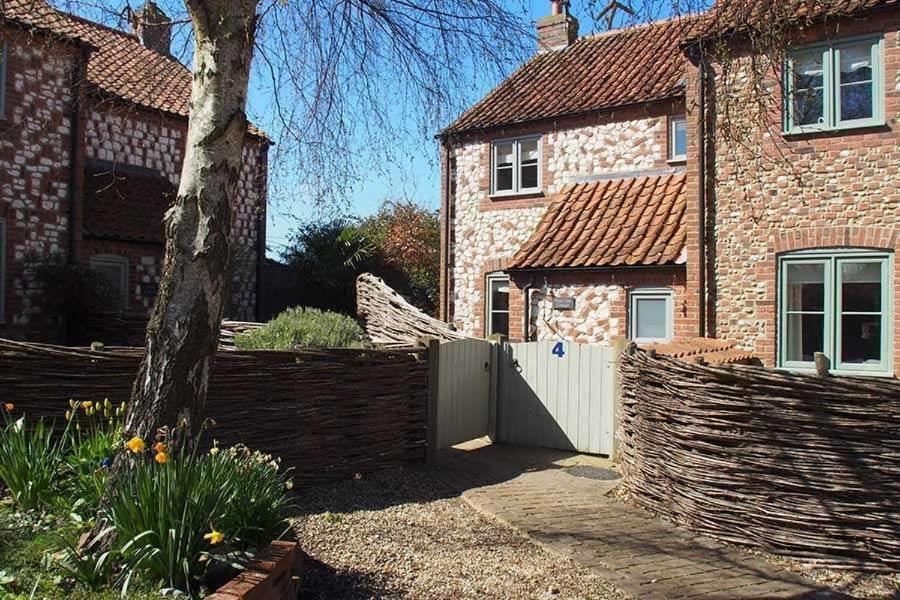a fence in front of a house with a gate at Plum Tree Cottage, Burnham Market By Together Travel in Burnham Market