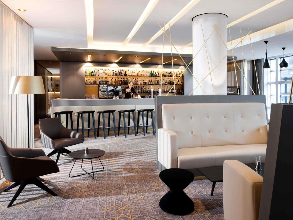 a lobby with a bar with a couch and chairs at Sofitel Luxembourg Europe in Luxembourg
