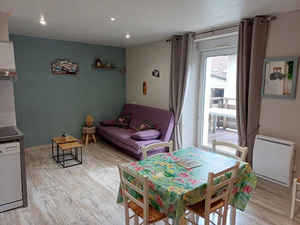 een woonkamer met een tafel en een paarse bank bij Entre Montagnes et Lacs in La Bresse