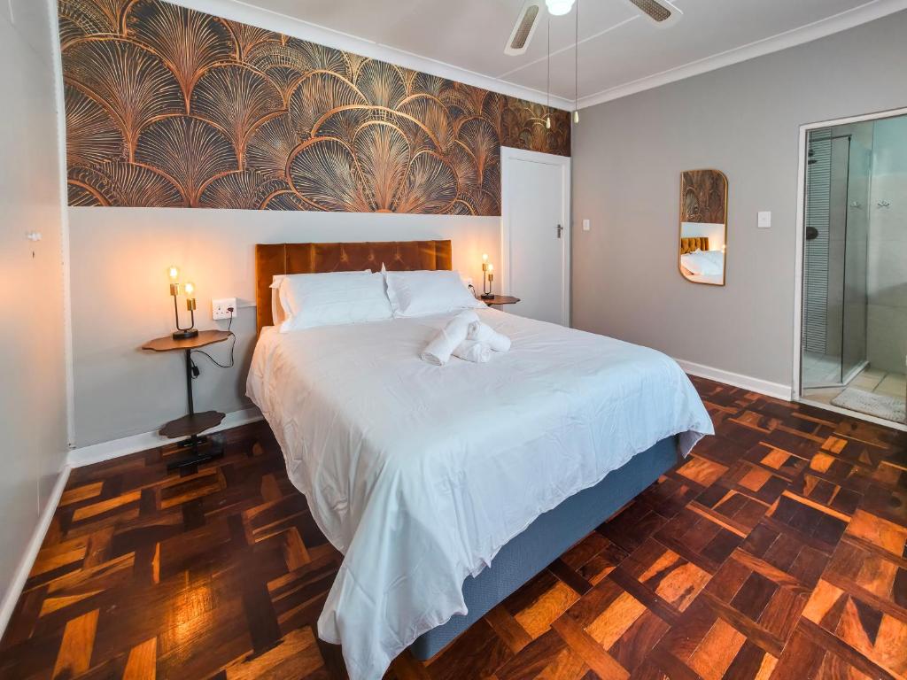 a bedroom with a large white bed and a wooden floor at Tau Golden Mane in Johannesburg