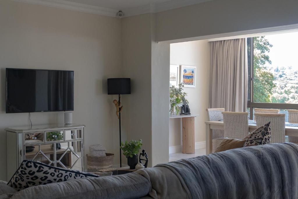 een woonkamer met een bank en een televisie bij Begonias Eden in Helderberg College
