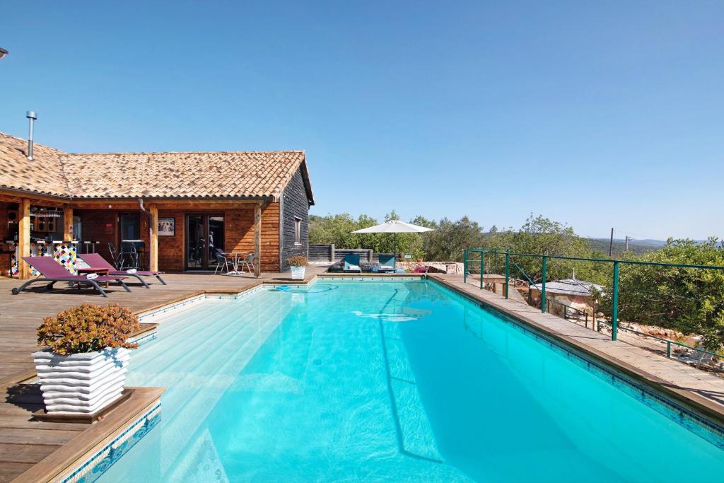 a large swimming pool with a deck and a house at Chambre D'hôtes Naturistes Nudistes in Monte da Charneca