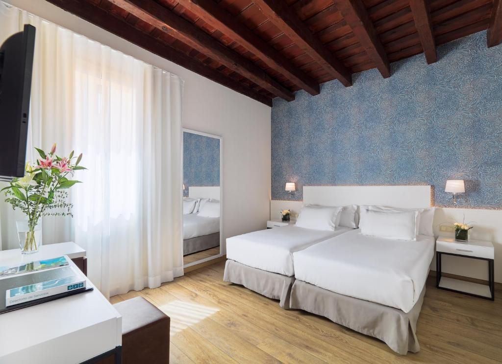 Un dormitorio con dos camas blancas y una pared azul. en H10 Raco del Pi, en Barcelona