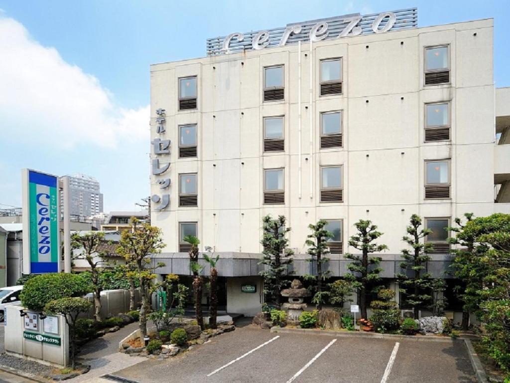 a white building with a parking lot in front of it at Hotel Cerezo in Tokyo