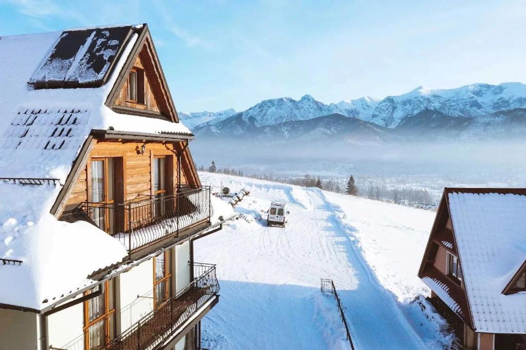 un bâtiment recouvert de neige avec des montagnes en arrière-plan dans l'établissement Zielony Domek Pokoje z widokiem na góry i sauną, à Kościelisko