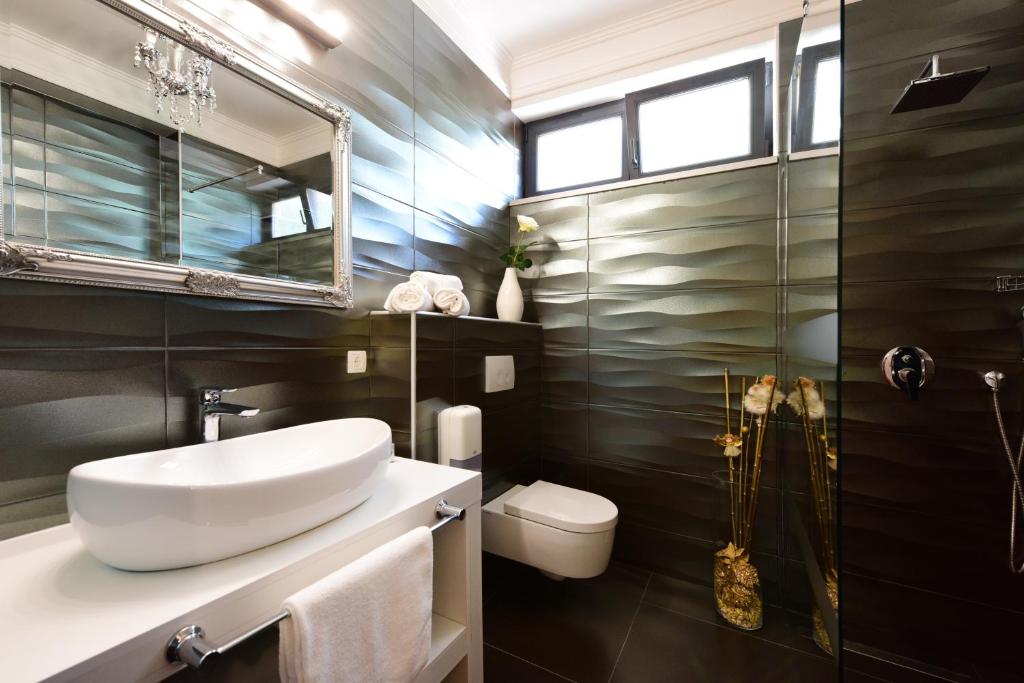 a bathroom with a sink and a toilet and a mirror at Hotel Sky in Zadar