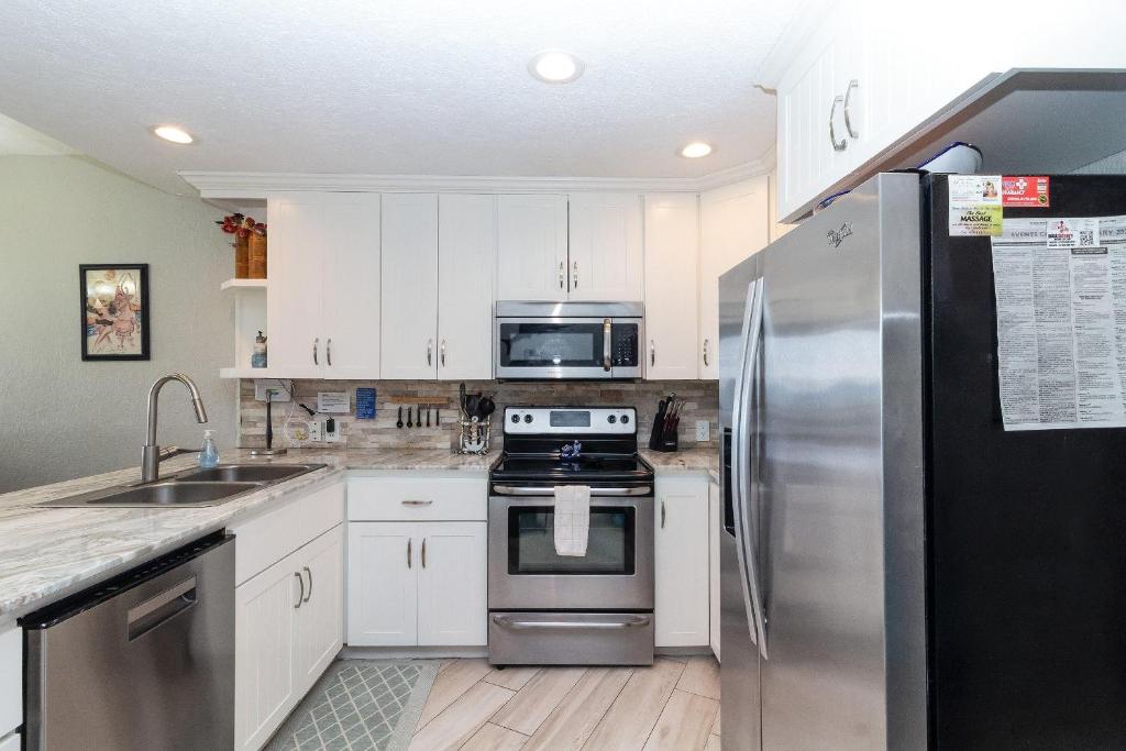 Una cocina con gabinetes blancos y un refrigerador de acero inoxidable. en Sonoran Spa E108, en Campo del Medio
