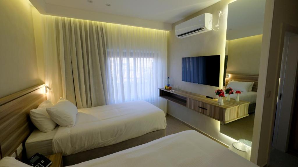 a hotel room with two beds and a television at Harmony City Hotel - Jerusalem in Jerusalem