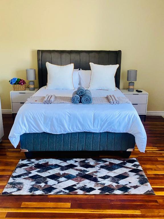 a bedroom with a bed with two pillows and a rug at PJ Guest House in Gqeberha
