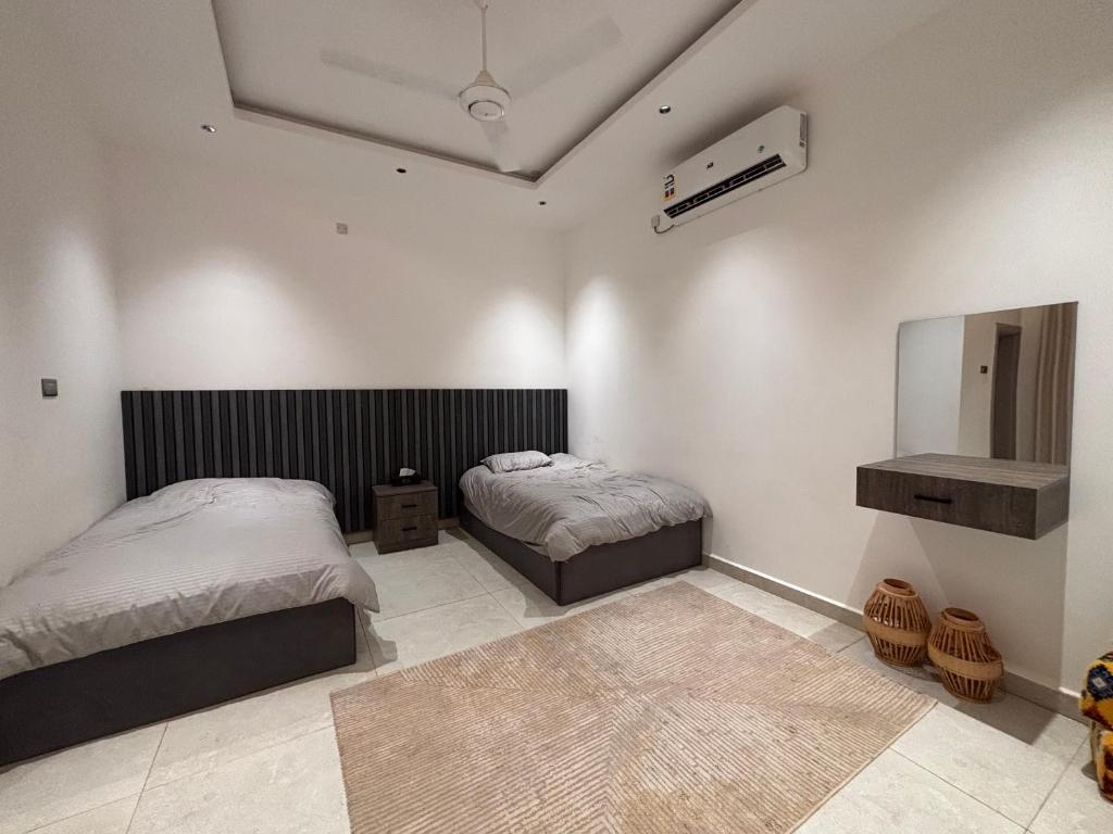 Un dormitorio con dos camas y un espejo. en شاليه خيال, en Sanāw