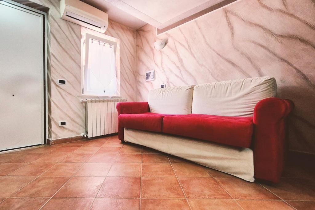 a red couch sitting in a room with a window at Studio apartment in Rome with a pool in Colonna