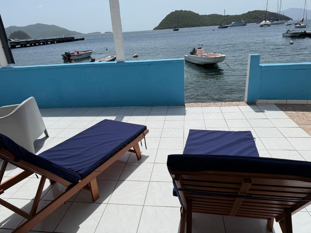 a patio with two chairs and a boat in the water at KazParadis les Saintes in Terre-de-Haut