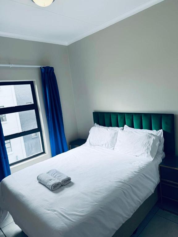 a bed with a green headboard and two towels on it at One on Heather Midrand 