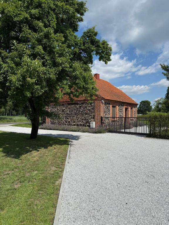 a brick house with a tree and a driveway at Agroturystyka Polanka in Olesiec
