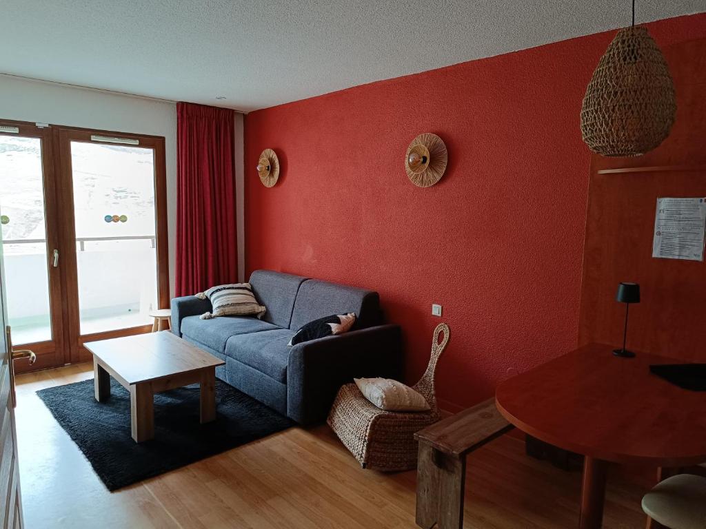 Un cocon en plein cœur de la Mongie في لا مونجي: غرفة معيشة مع أريكة زرقاء وجدار احمر