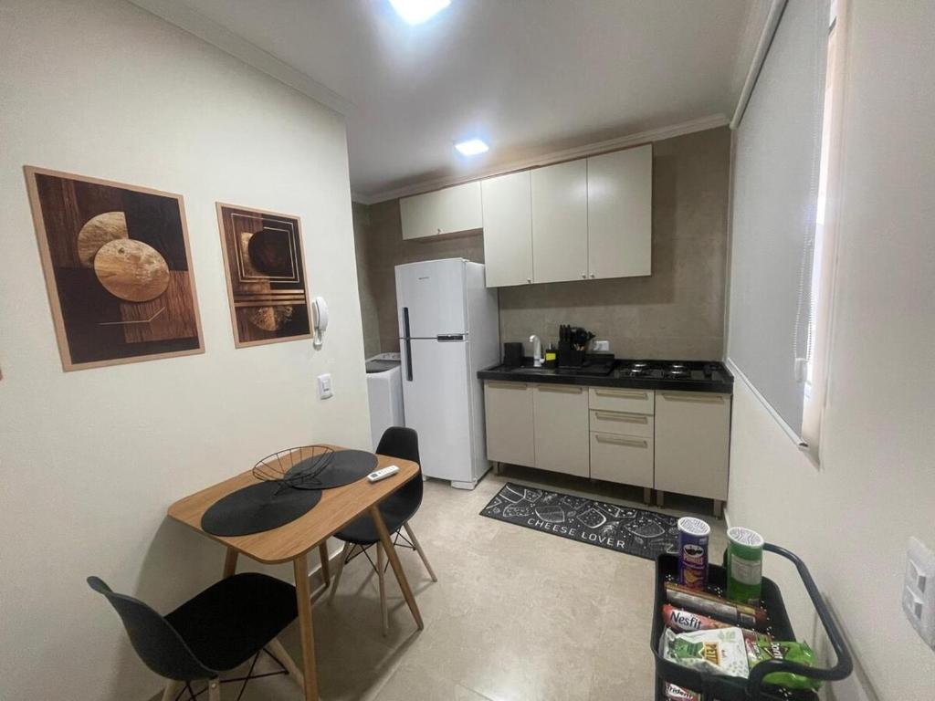 a small kitchen with a table and a refrigerator at Apartamento 01 quarto in Três Lagoas