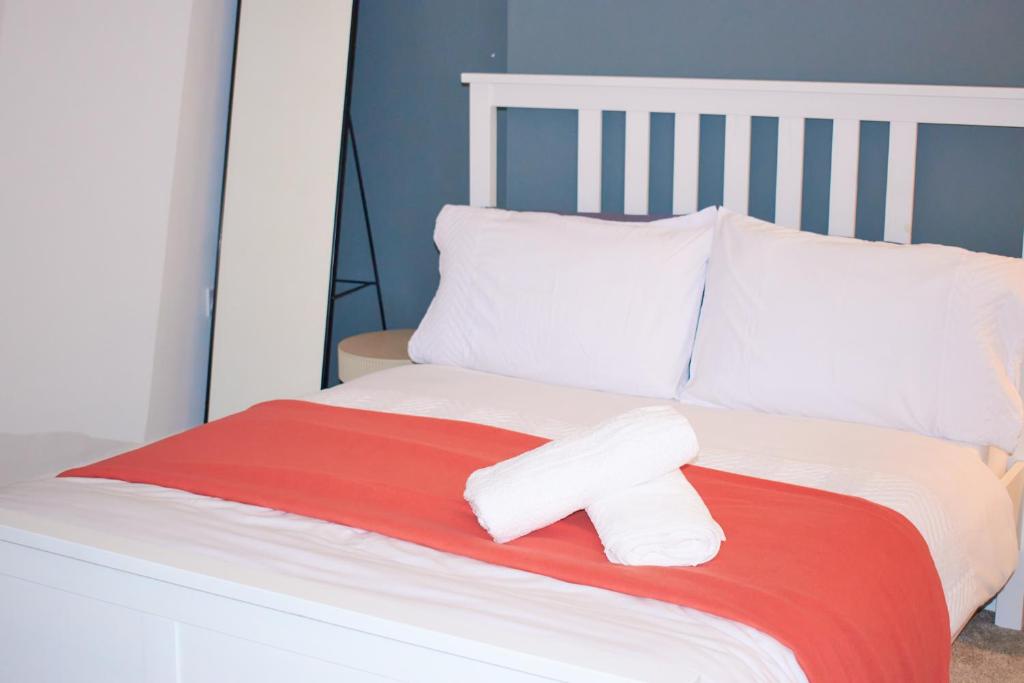 ein Bett mit zwei weißen Kissen und einer roten Decke in der Unterkunft 3-Bedroom House Close to City Centre and M5 with Garden and Parking in Bristol