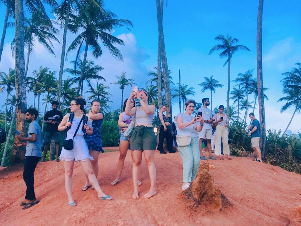 Un grupo de personas de pie en una playa con palmeras. en Khongaha Villa Holiday Home, en Mirissa