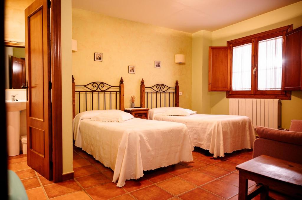 a room with two beds with white sheets at Casa Rural La Milagrosa in San Martín de Moncayo