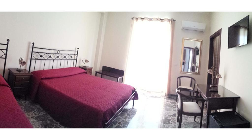 a bedroom with a red bed and a desk and a window at B&B Capo Sant'Alessio in SantʼAlessio Siculo