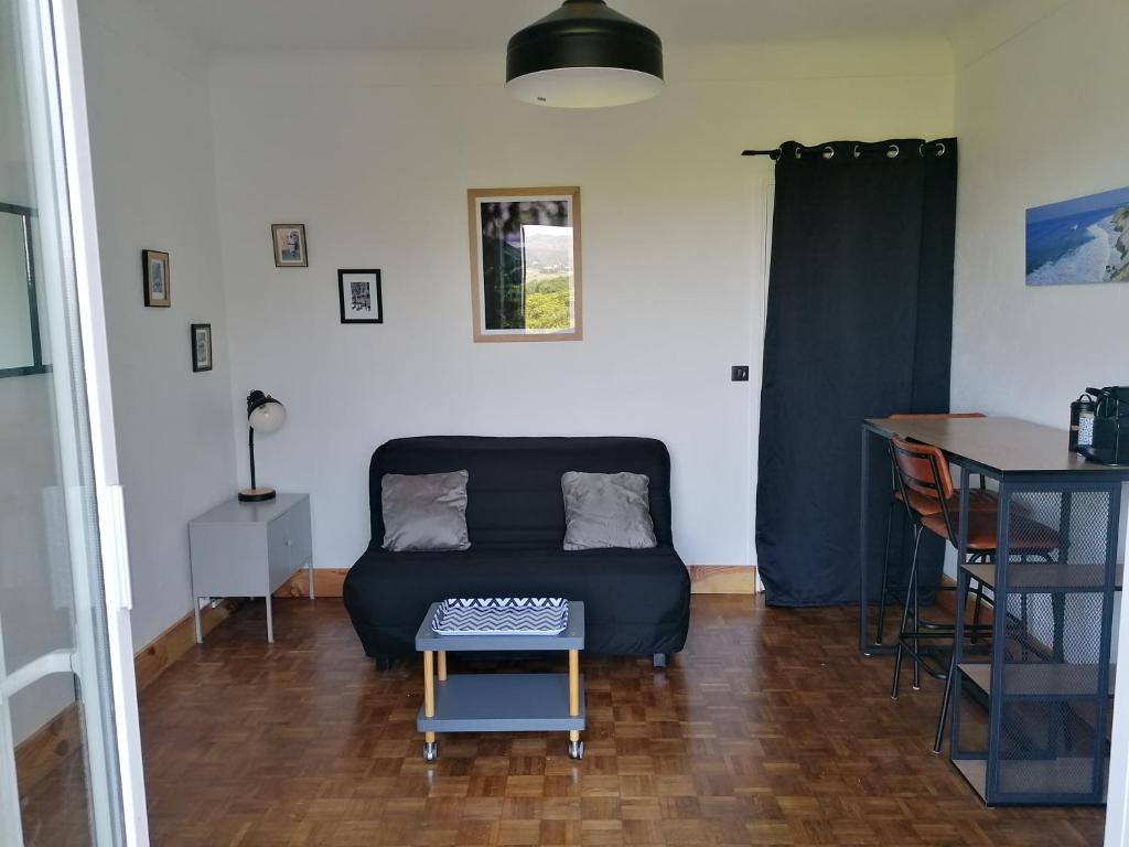 una sala de estar con un sofá y una mesa en Chambre indépendante avec WC et salle de bain, en Urrugne