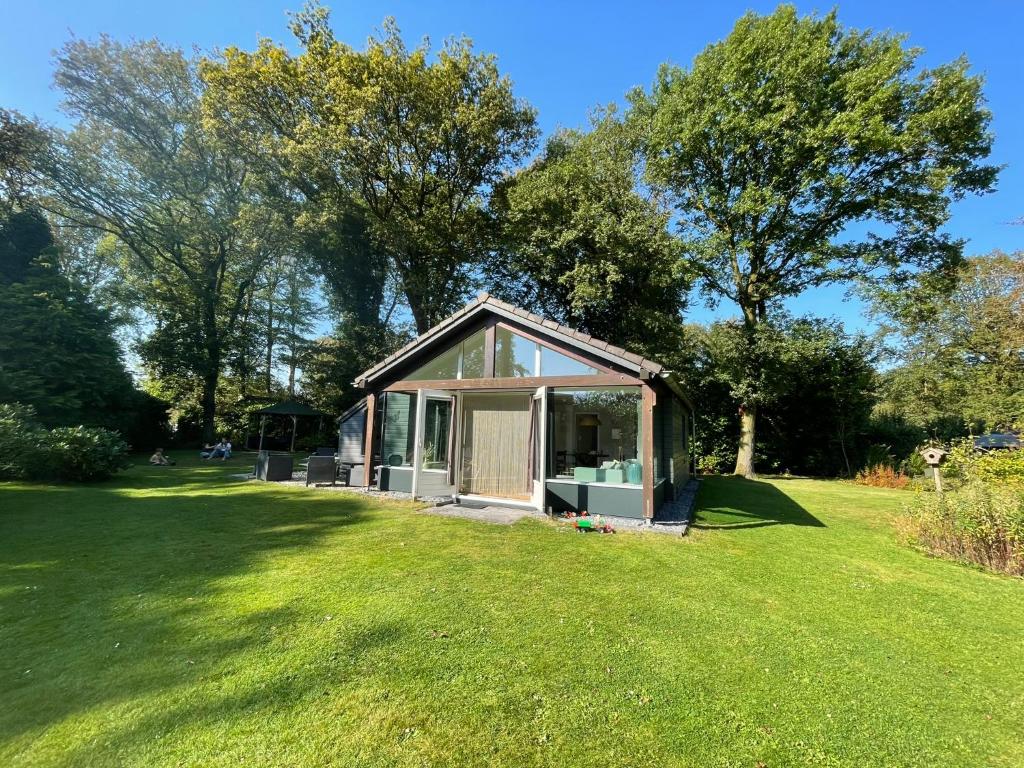 a small house in a grassy field with trees at Vakantiewoning De Vlinder, Bakkeveen in Bakkeveen