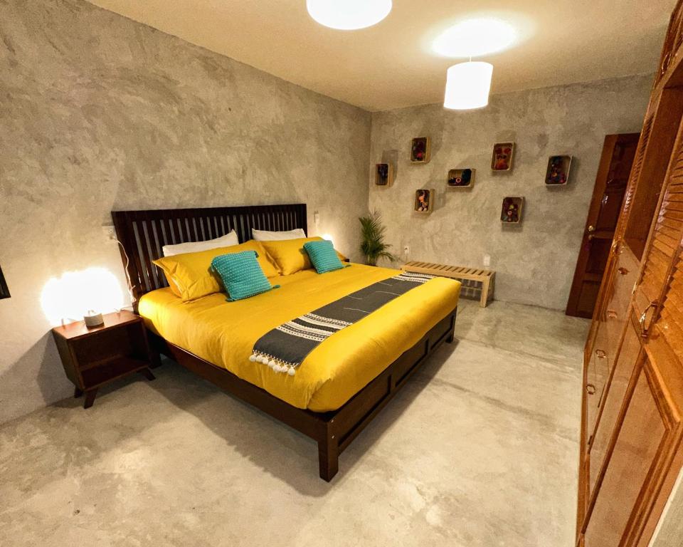 a bedroom with a bed with yellow sheets and blue pillows at Cozy home, walking distance San Cristobal in San Cristóbal de Las Casas