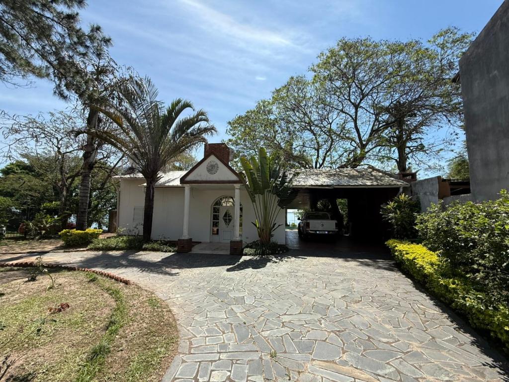 a house with a palm tree and a driveway at Casa al rio con muelle privado Paso de la Patria in Paso de la Patria