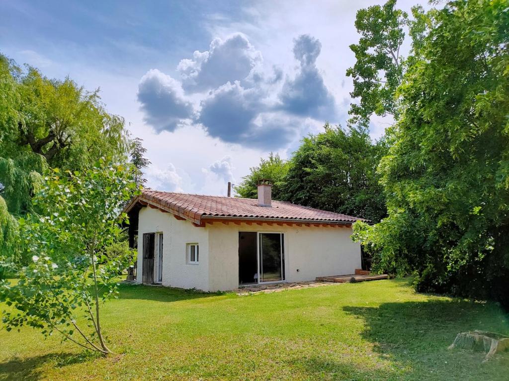 a small white house in the middle of a yard at Réveil au chant des Oiseaux in Chalain-le-Comtal