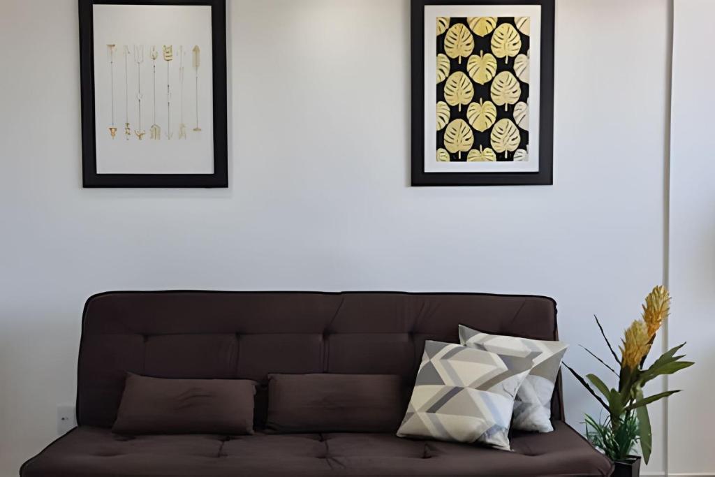 een woonkamer met een bruine bank en twee ingelijste foto's bij Apartamento Brisa do Mar in Natal